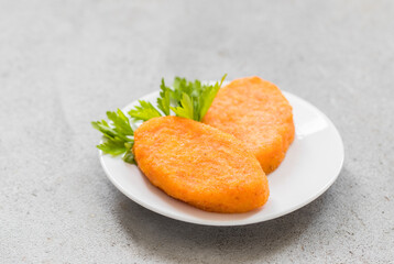 Vegan Carrot cutlets with parsley, on a plate. Light grey background. Copy space