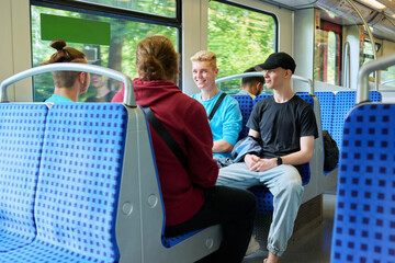 Young male friends sitting inside the train, talking laughing together