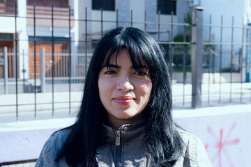 portrait of young venezuelan latina woman with bangs standing outdoors at sunset looking at camera