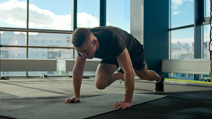 Caucasian sportsman sport trainer doing mountain climber exercise running plank on fitness mat male...