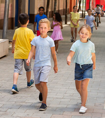 Group of children walking on city street in fine weather