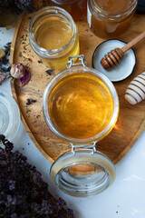fresh natural  linden honey in big glass jar  at wooden tray with wooden  honey spoons around herb flowers . close up. flat lay