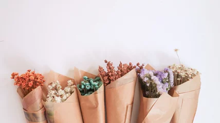 Tuinposter Flowers in bunches, herbs, dried flowers in kraft packaging on white background, top view, space for text. High quality photo © Катя Мазурец