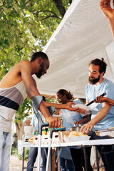 Detailed image of caucasian male volunteer serving free food to the needy african american man on...