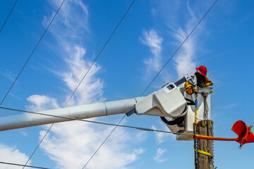 Electrical lineman in crane working on an electric pole damaged by supercell