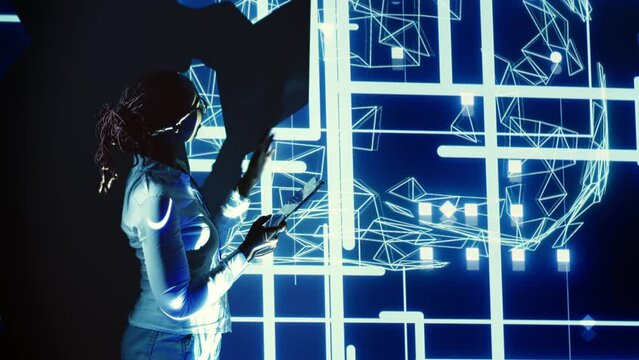System administrator programming in AI server farm housing advanced equipment used for machine learning training. Programmer running code on tablet to update artificial intelligence rigs