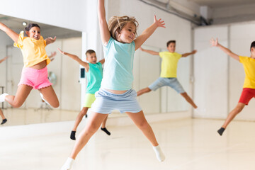 Happy children jumping while studying modern style dance in class indoors