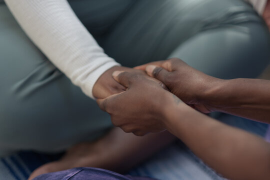 A woman receives a hand massage from her friend. Her friend rubs her hand gently, showing a moment of connection as well as physical and emotional support between two people.