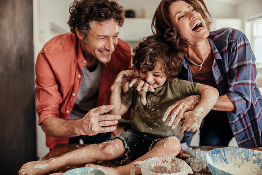 Young caucasian family being messy and having fun baking together in the kitchen