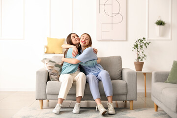 Obraz premium Female friends hugging on sofa at home