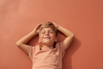 a young boy lies on ground while smiling, in the style of minimalist backgrounds, terracotta, babycore,