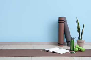 Magazine with mobile phone, dumbbells and bottle on fitness mat in gym