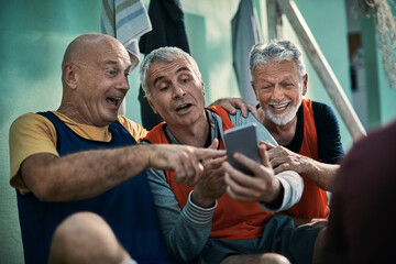 Group of seniors using a smartphone in a locker room after playing football