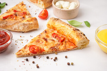 Pieces of tasty pizza Margarita with basil and bowl of mozzarella on white background