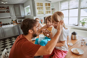 Young family having breakfast together and being messy in the kitchen