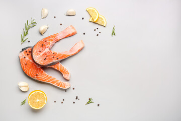 Raw salmon steaks and different spices on grey background