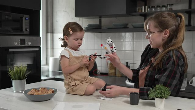 small girl toddler and mother or aunt play with finger puppets at home