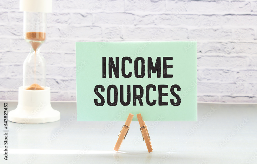Poster income sources wooden table with notepad. text on a notepad page.