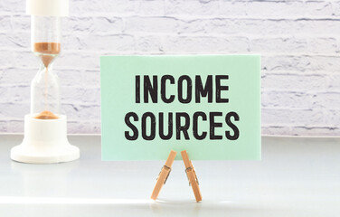 Income sources wooden table with notepad. text on a notepad page.
