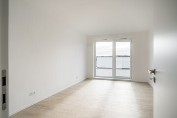 Empty unfurnished room in new apartment. The room has large window and wooden floor. Walls are...