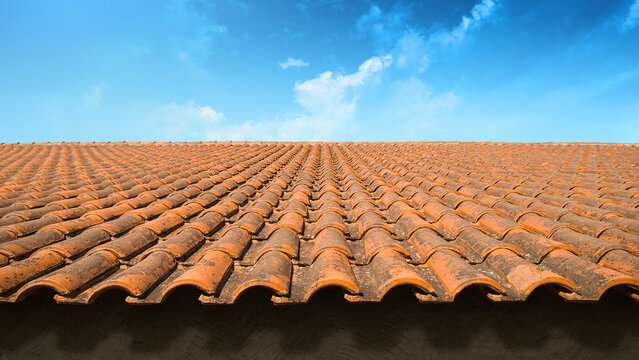 Weathered red tile roof with midday overhead sunlight on a blue sky background