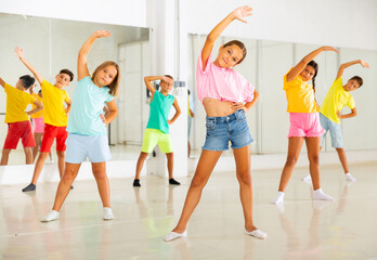 Fototapeta premium Smiling girls and boys doing dance workout during group class in fitness center
