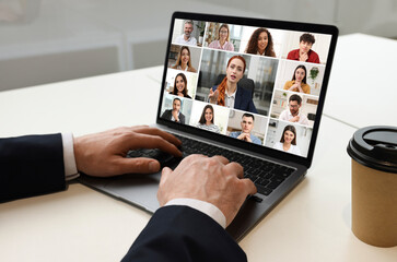 Man participating in webinar via laptop at table, closeup