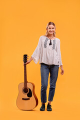 Happy hippie woman with guitar on yellow background