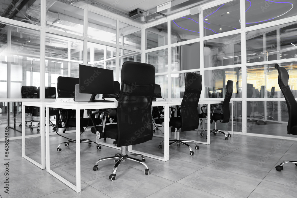 Wall mural Stylish interior of open plan office. Workspace with computers, tables and chairs