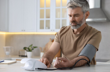 Man measuring blood pressure at table indoors