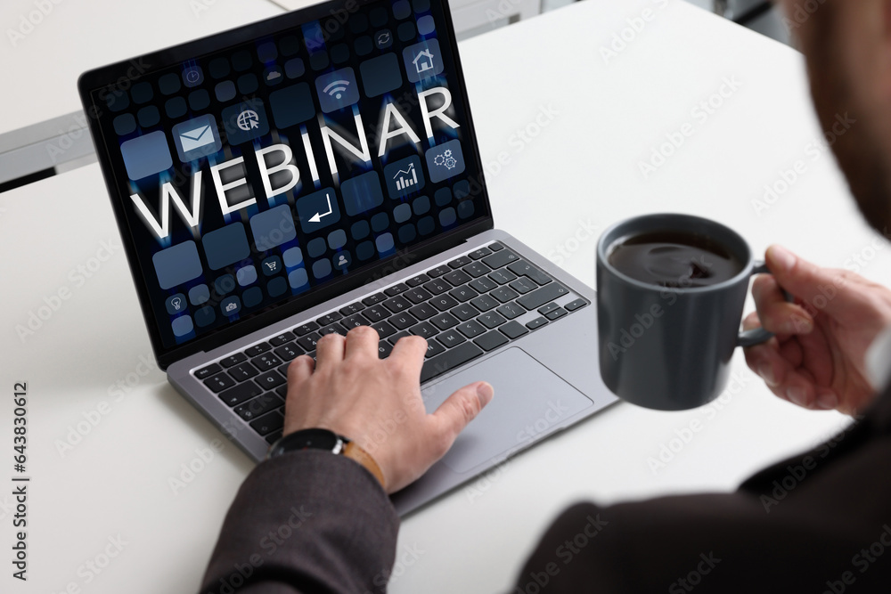 Sticker Online webinar, web page on computer screen. Man with cup of coffee using laptop at white table, closeup