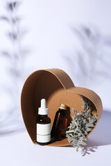 Heart shaped box with cosmetic products and silver leaves on white background