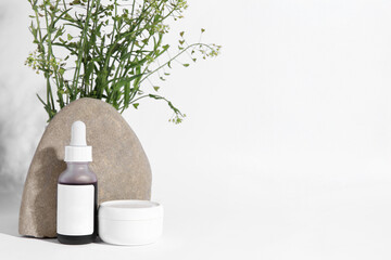 Cosmetic products, stone and bunch of camelina sativa on white background. Space for text