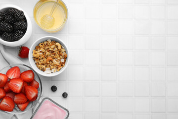 Tasty oatmeal, fresh berries, yogurt and honey on white tiled table, flat lay with space for text. Healthy breakfast