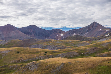 Fototapeta na wymiar Mountain peaks with waves of tundra hills and overcast skies