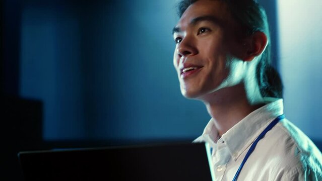 Close up shot of happy employee wandering around data center infrastructure providing processing resources for different workloads. Smiling admin doing analysis on servers