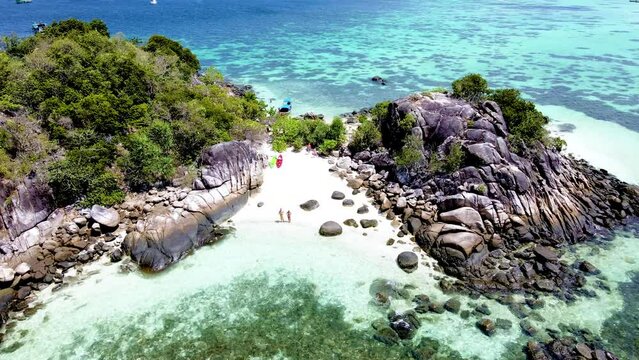 couple on the beach of Kla Island in front of Koh Lipe Island Southern Thailand, with turqouse colored ocean and white sandy beach with a kayak at Ko Lipe on a sunny day