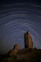 A lengthy star trail arcs across the night sky above the Vingerklipp, Damaraland, Namibia.
