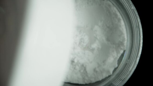 I unscrew the lid of the creatine powder jar, and the camera zooms in, capturing a macro shot as it descends inside.