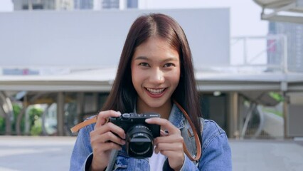 Young asian woman smiling and looking at camera, tourist female using camera vintage with backpack - Powered by Adobe