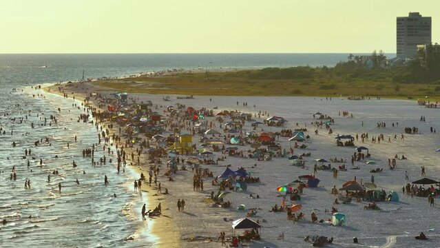 High angle view of crowded Siesta Key beach in Sarasota, USA. Many people enjoing vacations time swimming in ocean water and relaxing on warm Florida sun at sundown