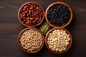 Fototapeta premium Top view of assorted beans in a wooden bowl on a wooden table