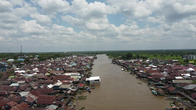 Aerial view of the City on the river's banks with the activity of boats speeding over the river. Pangkalan Bun, central kalimantan, Indonesia - 25 August 2023