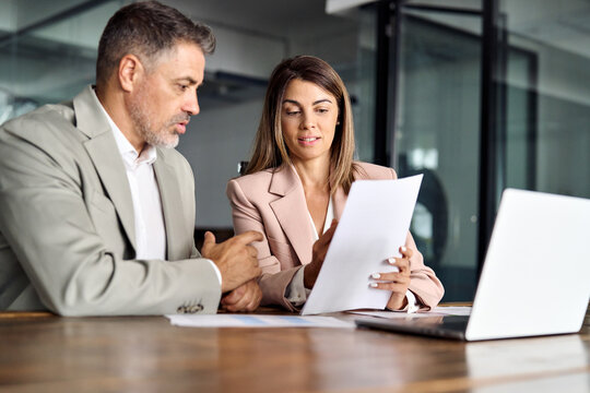 Business woman lawyer manager holding legal documents consulting mature older client at office meeting, two professional executives experts discussing financial accounting papers working together.
