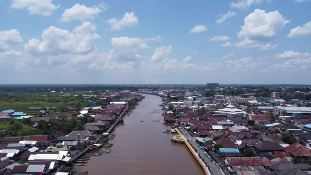 Aerial view of the City on the river's banks with the activity of boats speeding over the river. Pangkalan Bun, central kalimantan, Indonesia - 25 August 2023