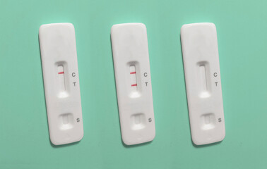 Set of three rapid antigen tests (RAT). The tests are showing a negative and a positive result. One is unused. There are no markings on the test. Rapid antigen detection test (RADT)