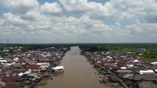 Aerial view of the City on the river's banks with the activity of boats speeding over the river. Pangkalan Bun, central kalimantan, Indonesia - 25 August 2023