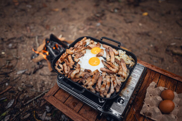 Fried eggs and grilled pork in a camping pan