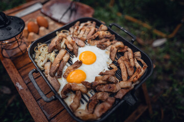 Fried eggs and grilled pork in a camping pan
