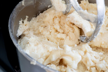 Light cream-colored dessert flour In a stainless steel mixing pot with batter leaves on top, top angle shot, baking concept